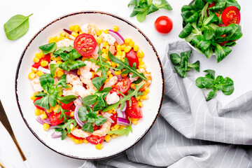 Delicious shrimp salad with sweet corn, cherry tomatoes, lamb lettuce and red onion on white table background. Top view