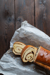 Cinnamon cake baked in a loaf pan and served whole and sliced with baking paper isolated on dark wooden table background. Flat lay with copy space
