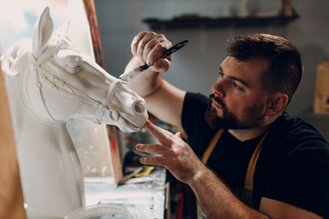Artisan craftsman create horse based on plaster cast. Gypsum mold and plastic mask sculpting and painting
