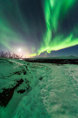 Fototapeta na wymiar imagen de un paisaje nevado nocturno con montañas al fondo y una aurora boreal sobre el cielo de Islandia 