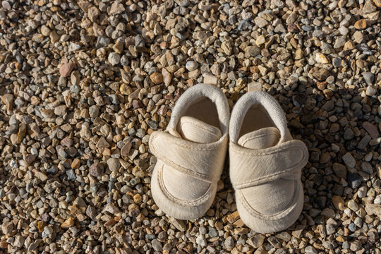 赤ちゃんの靴とたくさんの小石。靴に小石が入るイメージ