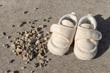 Fototapeta na wymiar 赤ちゃんの靴とたくさんの小石。靴に小石が入るイメージ