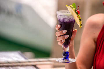 colorful gin tonic cocktails in glasses on on hand in yacht and sea background. hand cheers glass...