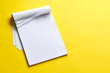 Top view of blank open notebook with torn pages. Page with lines on yellow background with copy...