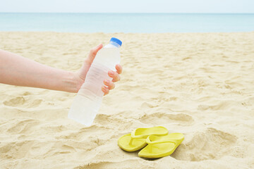 Woman holds a plastic bottle with clean drinking water in her hand against the background of a...