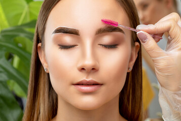 The make-up artist does Long-lasting styling of the eyebrows and will color the eyebrows. Eyebrow lamination. Professional make-up and face care. - obrazy, fototapety, plakaty