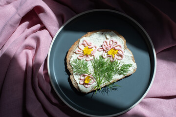 creative sandwich with soft cheese and pink pasta tarama greens, flowers