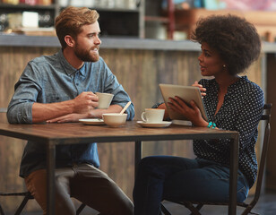 Should we order something to eat. a young couple using a digital tablet together on a coffee date.