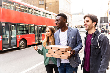 Happy friends with takeaway pizza in London