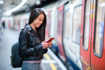 Chinese woman at underground train station using mobile phone - obrazy, fototapety, plakaty