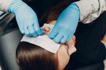 Young woman doing ear piercing at beauty studio salon