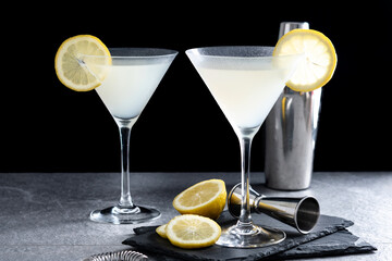 Lemon drop martini cocktail on gray stone and black background