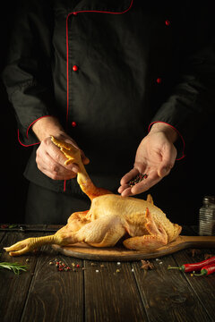 The chef prepares raw rooster in the kitchen. The cook adds black pepper to the cock before frying. Preparing to cook fried chicken