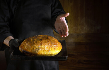 The baker presents freshly baked wheat bread in the bakery. Place for advertising. The concept of...