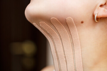 Close-up of a tape on the neck of a young woman. Kinesiotherapy with therapeutic tapes - obrazy, fototapety, plakaty