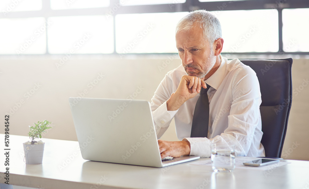 Poster that emails got his attention. a mature businessman using a laptop in an office.