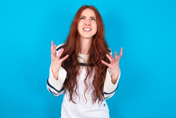 young caucasian woman wearing overalls over blue background crying and screaming. Human emotions,...