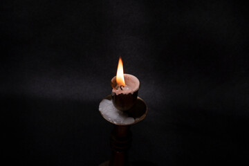 Antique bronze candlestick with a candle on the table on a black background