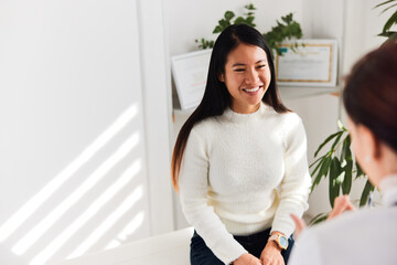 Asian female patient has a pleasant informal conversation with the caring doctor.