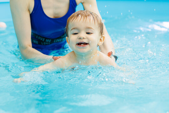 A 2-year-old little boy learns to swim in a pool with a coach. Swimming lessons for children
