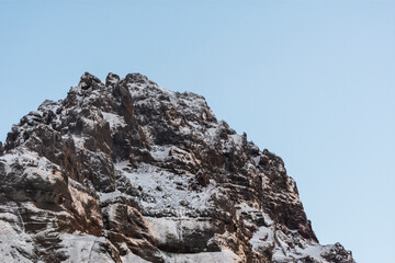 Fototapeta na wymiar imagen detalle de la cima de la montaña con nieve y claros oscuros y el cielo azul de fondo 