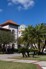 Fototapeta na wymiar Vertical view of one of Flagler’s College Spanish Revival buildings and the dome of the 1889 Memorial Presbyterian Church seen during a sunny winter day, St. Augustine, Florida, USA