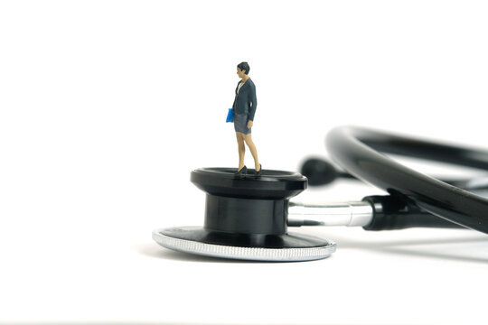 Miniature people toy figure photography. Medical checkup schedule concept. A businesswoman standing above stethoscope. Isolated on white background