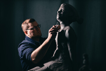 Man sculptor creates sculpt bust clay human woman sculpture. Statue craft creation workshop.