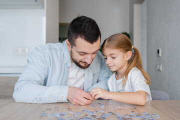 man playing puzzle with daughter at home.