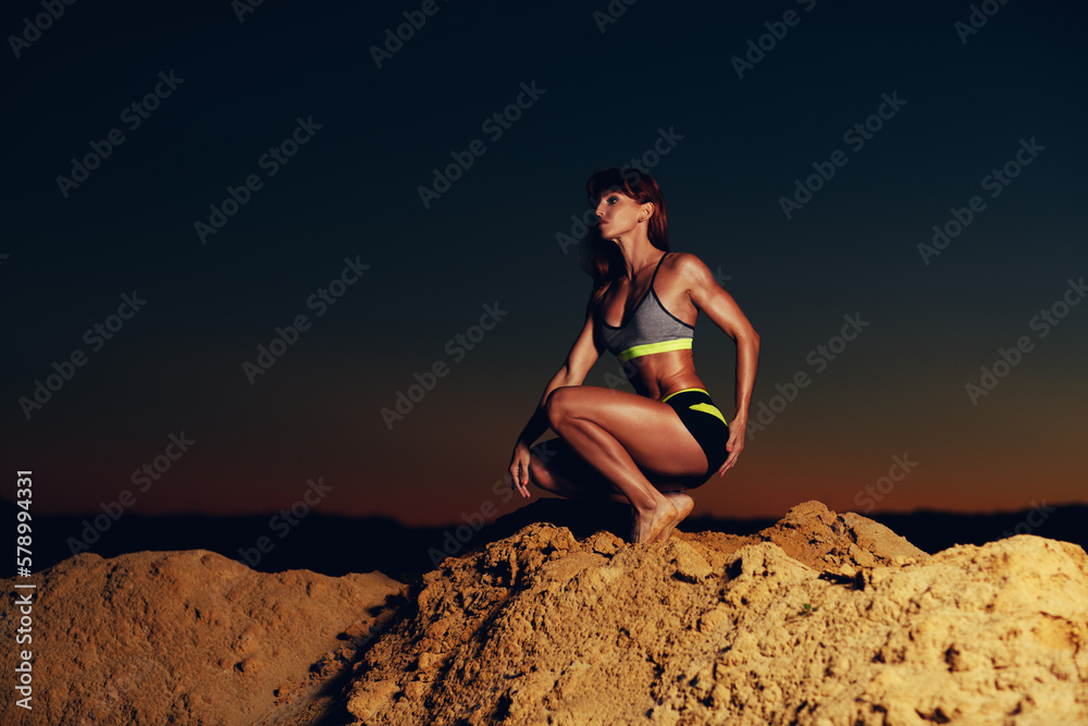 Wall mural Young slim sports woman at the top of mountain, dark vibrant twilight colors