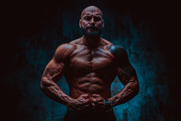 Naklejka na ściany i meble Strong man bodybuilder on dark background