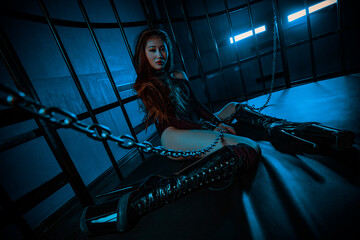 Young asian woman sitting in cage with chains bdsm style portrait