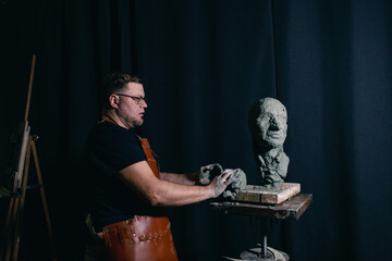 Man sculptor creates sculpt bust clay human woman sculpture. Statue craft creation workshop.