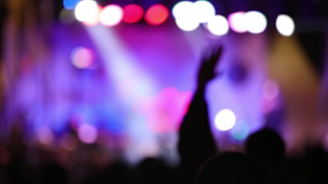 Silhouettes of concert crowd with stage lights, out of focus blurred video.	
