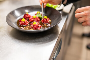 professional chef's hands cooking Raw beef meat tartar in restaurant kitchen