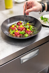 professional chef's hands cooking Raw beef meat tartar in restaurant kitchen