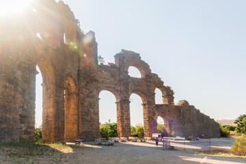 Ruined Roman aqueduct at Aspendos against light in summer day. Aqueduct is a part of water supply ancient system. Antalya region, Turkey (Turkiye). History and archaeology background