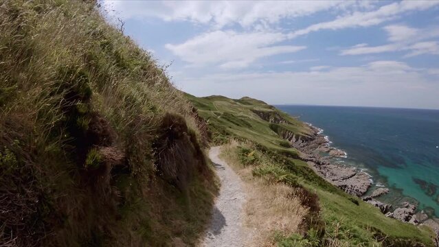 Walking along the trail, natural coastal scenery. South West Coast path, rocky coast near Woolacombe, Devon, UK. First person view. 
