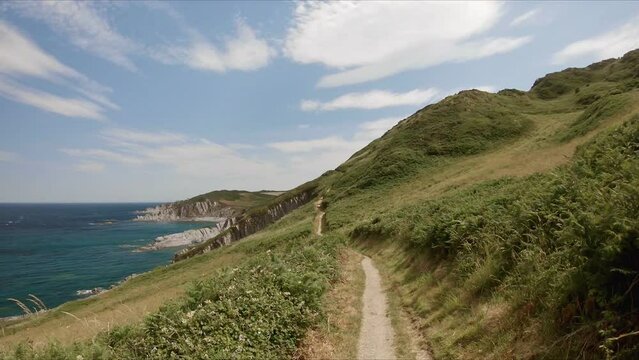 Walking along the trail, South West Coast path, rocky coast near Woolacombe, Devon, UK. First person view. 