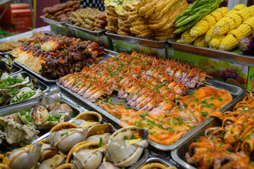 From above of assorted fresh seafood and boiled corns placed in containers on stall in local bazaar in Vietnam