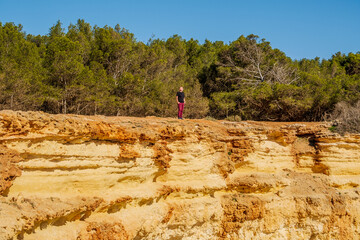 A man standing on the top of the cliffs of Corredoura beach, Algarve, Portugal