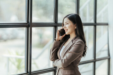 Asian businesswoman in formal suit in office happy and cheerful during using smartphone and working