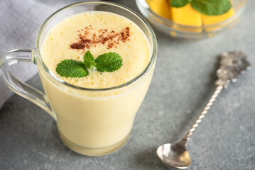 Lassi mango close-up. Traditional Indian drink, gray background. Refreshing milkshake. Side view, selective focus, copy space