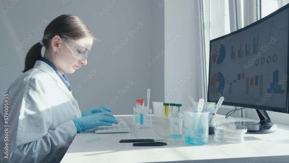 Poster a female researcher sits at a workplace in a laboratory, behind a personal computer monitor. against
