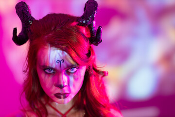 Beautiful young woman with makeup zodiac signs of Aries sign horoscope. Girl with horns on head in neon light.