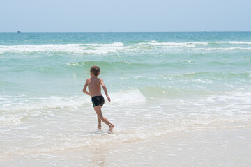 Fototapeta premium happy boy running on the waves of the sea