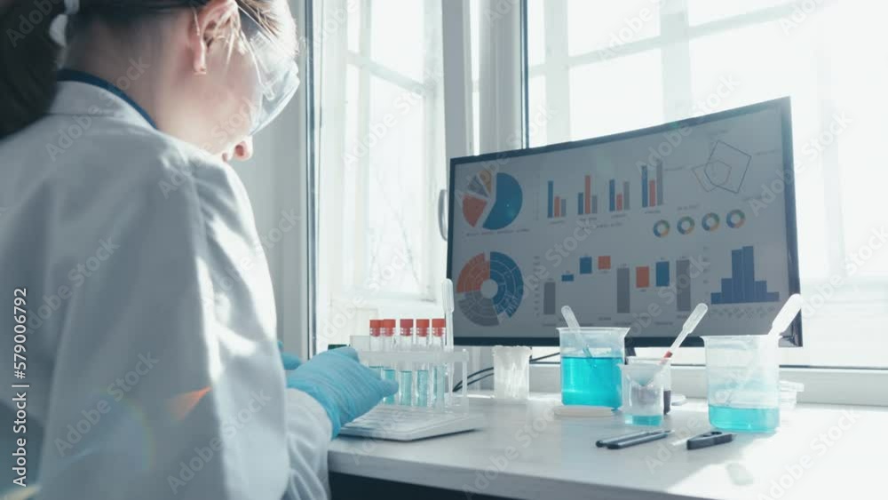 Poster a female researcher sits at a workplace in a laboratory, behind a personal computer monitor. against