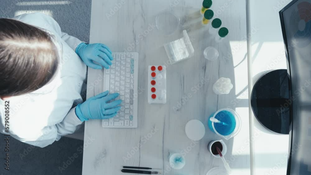 Poster a female researcher sits at a workplace in a laboratory, behind a personal computer monitor. against