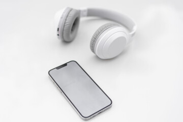 White headphones and smartphone, blank background for white text.
