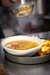 chef pouring tasty soup from pot into bowl on kitchen